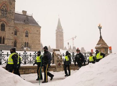 Police officers walk pass the Parliament buildings in Ottawa on Sunday, Feb. 20, 2022. (Adrian Wyld/The Canadian Press via AP)