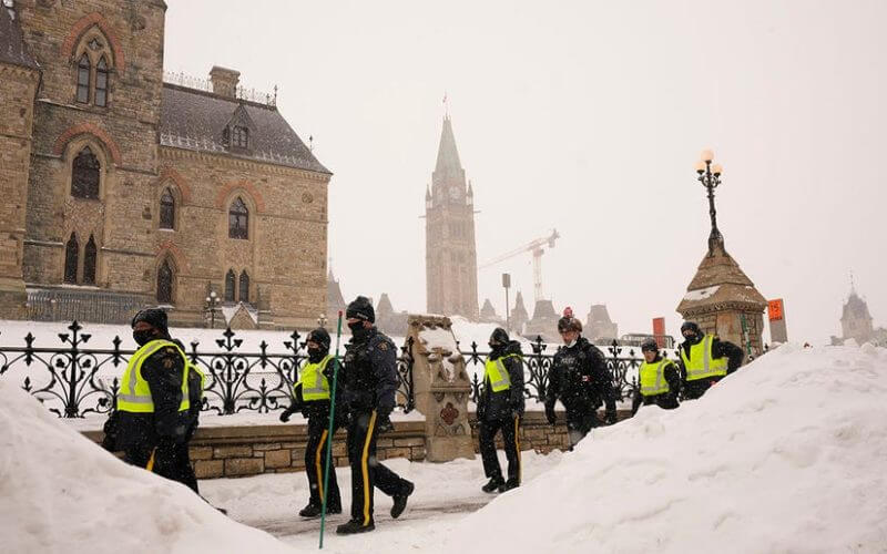Police officers walk pass the Parliament buildings in Ottawa on Sunday, Feb. 20, 2022. (Adrian Wyld/The Canadian Press via AP)