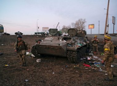 Ukrainian servicemen are seen next to a destroyed armoured vehicle, which they said belongs to the Russian army, outside Kharkiv, Ukraine February 24, 2022. REUTERS/Maksim Levin