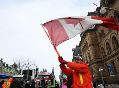 A man waves the flag of Canada around parked trucks, as protests against coronavirus disease (COVID-19) vaccine mandates continue, in Ottawa, Ontario, Canada, February 16, 2022. REUTERS/Shannon Stapleton