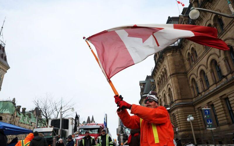 A man waves the flag of Canada around parked trucks, as protests against coronavirus disease (COVID-19) vaccine mandates continue, in Ottawa, Ontario, Canada, February 16, 2022. REUTERS/Shannon Stapleton