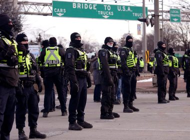 Police line up in preparation to enforce an injunction against a demonstration that has blocked traffic across the Ambassador Bridge by protesters against COVID-19 restrictions, in Windsor, Ontario, on Sat., Feb. 12, 2022. (Nathan Denette /The Canadian Press via AP)