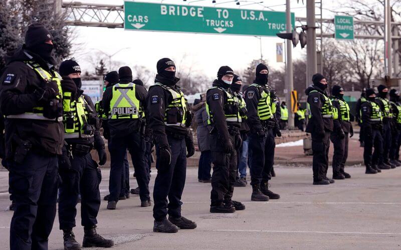 Police line up in preparation to enforce an injunction against a demonstration that has blocked traffic across the Ambassador Bridge by protesters against COVID-19 restrictions, in Windsor, Ontario, on Sat., Feb. 12, 2022. (Nathan Denette /The Canadian Press via AP)