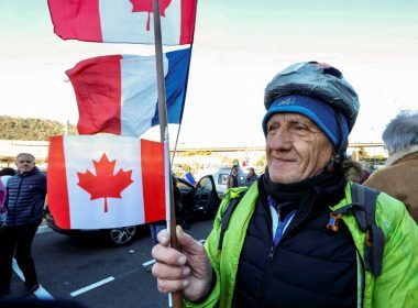 A French activist holds a Canadian flag before the start of their "Convoi de la liberte" (The Freedom Convoy), a vehicular convoy protest converging on Paris to protest coronavirus disease (COVID-19) vaccine and restrictions in Nice, France, February 9, 2022. REUTERS/Eric Gaillard