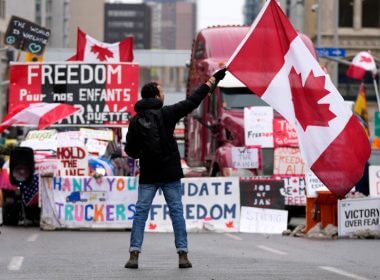 A protester waves a Canadian flag in front of parked vehicles on Rideau Street on the 15th day of a protest against COVID-19 measures that has grown into a broader anti-government protest, in Ottawa, Friday, Feb. 11, 2022. (Justin Tang/THE CANADIAN PRESS)
