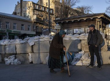 An elderly woman walks pass concrete blocks topped with sandbags at a street in Odesa, southern Ukraine, on Tuesday, March 22, 2022.(AP Photo/Petros Giannakouris)