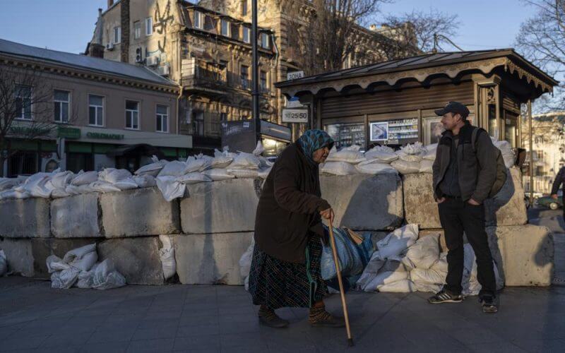 An elderly woman walks pass concrete blocks topped with sandbags at a street in Odesa, southern Ukraine, on Tuesday, March 22, 2022.(AP Photo/Petros Giannakouris)