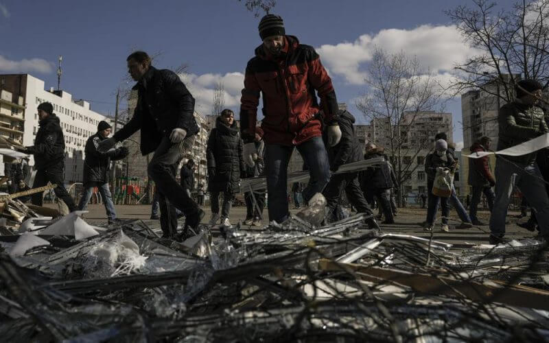 People clear debris outside a medical center damaged after parts of a Russian missile, shot down by Ukrainian air defense, landed on a nearby apartment block, according to authorities, in Kyiv, Ukraine, Thursday, March 17, 2022. Russian forces destroyed a theater in Mariupol where hundreds of people were sheltering Wednesday and rained fire on other cities, Ukrainian authorities said, even as the two sides projected optimism over efforts to negotiate an end to the fighting. (AP Photo/Vadim Ghirda)