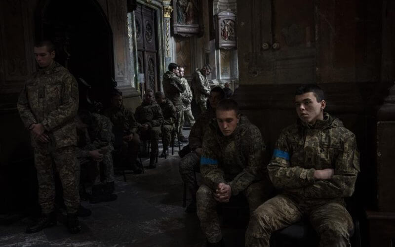Military cadets attend a funeral ceremony for four of the Ukrainian military servicemen, who were killed during an airstrike in a military base in Yarokiv, in a church in Lviv, Ukraine, Tuesday, March 15, 2022. At least 35 people were killed and many wounded in Sunday's Russian missile strike on a military training base near Ukraine's western border with NATO member Poland. (AP Photo/Bernat Armangue)
