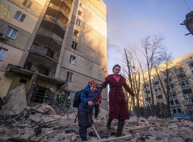 A woman with a child evacuates from a residential building damaged by shelling, as Russia's attack on Ukraine continues, in Kyiv, Ukraine, in this handout picture released March 16, 2022. Press service of the State Emergency Service of Ukraine/Handout via REUTERS