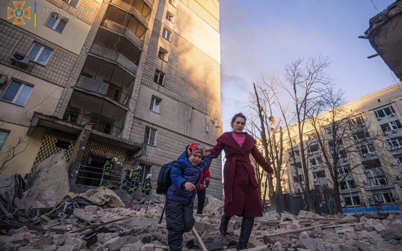 A woman with a child evacuates from a residential building damaged by shelling, as Russia's attack on Ukraine continues, in Kyiv, Ukraine, in this handout picture released March 16, 2022. Press service of the State Emergency Service of Ukraine/Handout via REUTERS