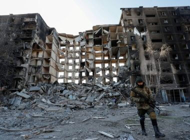 A service member of pro-Russian troops walks near an apartment building destroyed in the course of Ukraine-Russia conflict in the besieged southern port city of Mariupol, Ukraine March 28, 2022. REUTERS