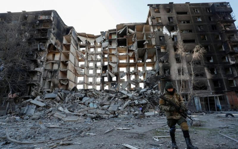 A service member of pro-Russian troops walks near an apartment building destroyed in the course of Ukraine-Russia conflict in the besieged southern port city of Mariupol, Ukraine March 28, 2022. REUTERS