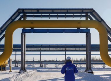 An employee in branded jacket walks past a part of Gazprom's Power Of Siberia gas pipeline at the Atamanskaya compressor station outside the far eastern town of Svobodny, in Amur region, Russia November 29, 2019. REUTERS/
