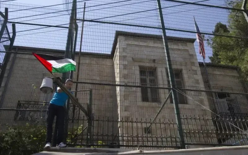 A man places a Palestinian flag on a fence surrounding the U.S. consulate during a rally in support of Palestinian President Mahmoud Abbas' bid for statehood recognition in the United Nations, in Arab East Jerusalem September 21, 2011 (photo credit: REUTERS/Ronen Zvulun)