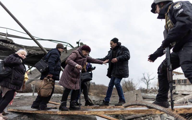 Local residents cross a destroyed bridge as they evacuate from the town of Irpin, after days of heavy shelling on the only escape route used by locals, while Russian troops advance towards the capital, in Irpin, near Kyiv, Ukraine March 7, 2022. REUTERS/Carlos Barria