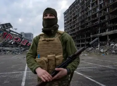 A Ukrainian soldier stands guard amid destruction caused by a March 21, 2022, shelling of a shopping center in Kyiv, Ukraine, March 30, 2022.