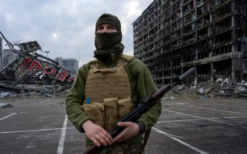 A Ukrainian soldier stands guard amid destruction caused by a March 21, 2022, shelling of a shopping center in Kyiv, Ukraine, March 30, 2022.