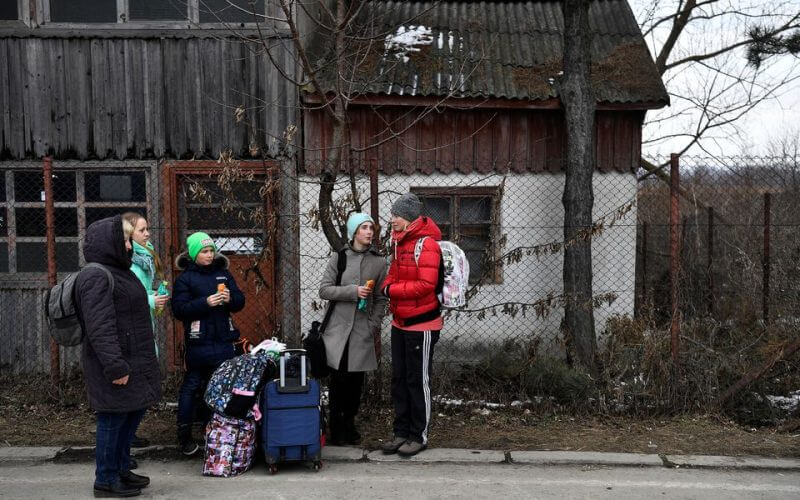 A family wait for transport after fleeing from Ukraine to Romania, following Russia's invasion of Ukraine, at the border crossing in Siret, Romania, March 13, 2022. REUTERS/Clodagh Kilcoyne