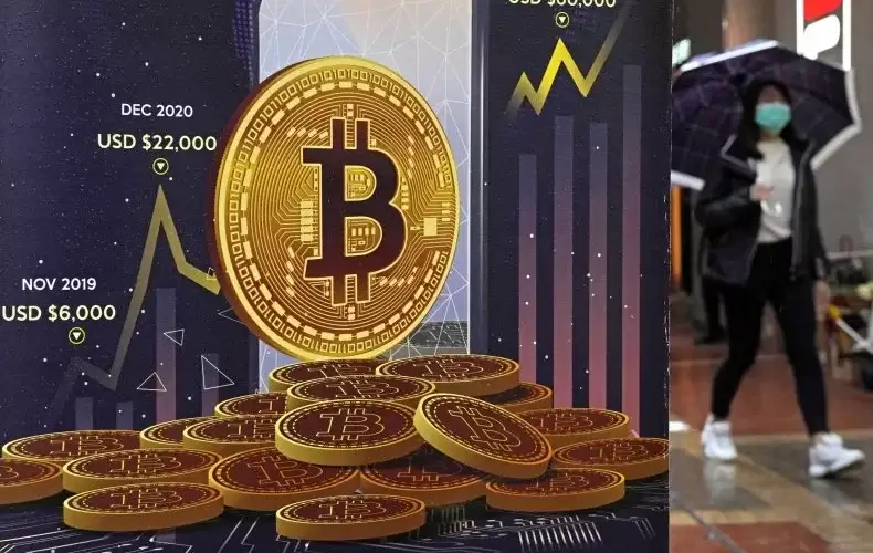 Russian and Ukrainian civilians are rapidly cashing in their national currencies for bitcoin as the Russian attack on Ukraine continues to take a steep financial toll on their economic sectors. Above, an advertisement for bitcoin cryptocurrency is displayed on a street in Hong Kong on February 17, 2022. KIN CHEUNG/AP PHOTO
