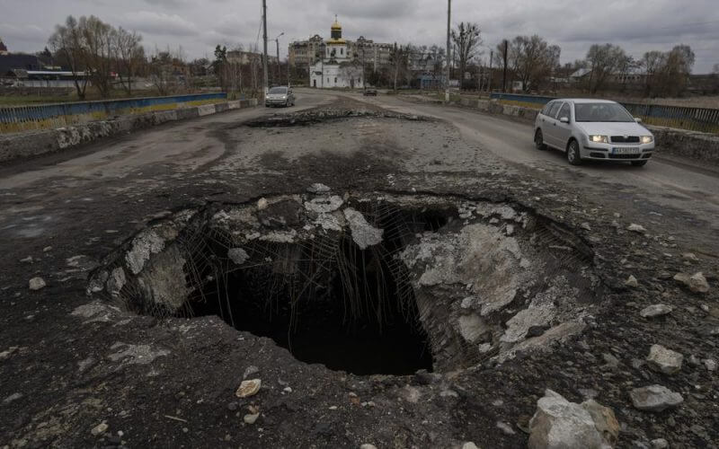 Cars drive near a damaged bridge following a Russian attack in the previous weeks in the town of Makarov, Kyiv region, Ukraine, on Sunday, April 10, 2022. (AP Photo/Petros Giannakouris)
