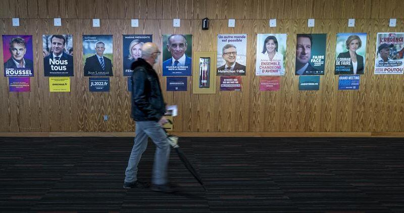 A French voter passes identification posters on his way to vote in the first round of the 2022 French presidential election, in Montreal, Saturday, April 9, 2022. (Peter McCabe/The Canadian Press via AP)