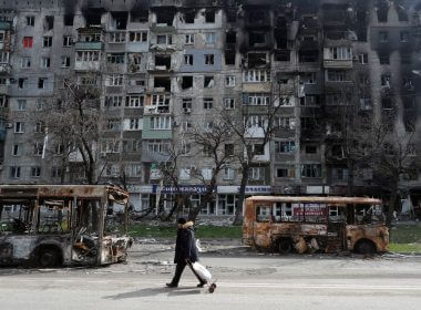 A local resident walks along a street past burnt out buses during Ukraine-Russia conflict in the southern port city of Mariupol, Ukraine April 19, 2022. REUTERS/Alexander Ermochenko