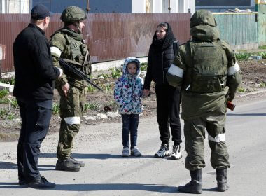 A woman with a child talks to service members of pro-Russian troops as evacuees board buses to leave the city during Ukraine-Russia conflict in the southern port of Mariupol, Ukraine April 20, 2022. REUTERS/Alexander Ermochenko