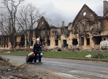 A woman pulls her bags past houses damaged during fighting in eastern Mariupol, Ukraine, Friday, April 8, 2022. | Alexei Alexandrov, file/AP Photo