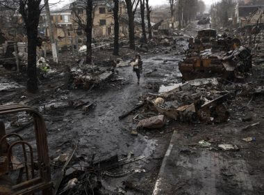 A woman walks amid destroyed Russian tanks in Bucha, in the outskirts of Kyiv, Ukraine, Sunday, April 3, 2022. (AP Photo/Rodrigo Abd)