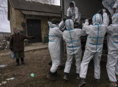 Nadiya Trubchaninova, 70, left, stands next to volunteers while loading a plastic bag that contains the body of a civilian killed by Russian soldiers into a truck, in Bucha, in the outskirts of Kyiv, Ukraine, Tuesday, April 12, 2022. (AP Photo/Rodrigo Abd)