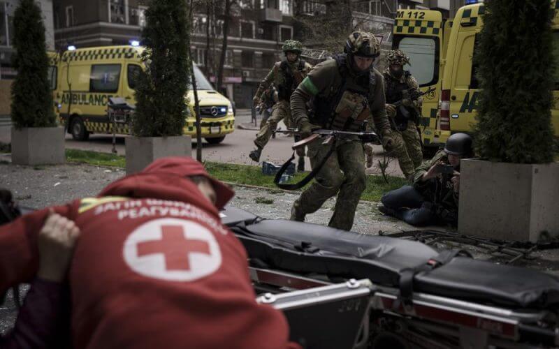 Ukrainian servicemen run for cover as explosions are heard during a Russian attack in downtown Kharkiv, Ukraine, Sunday, April 17, 2022. (AP Photo/Felipe Dana)