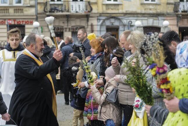 A Christian Orthodox priest blesses Ukrainians who hold pussy-willow branches as they celebrate Orthodox Palm Sunday in Lviv, Ukraine. Photo by Mykola Tys/EPA-EFE