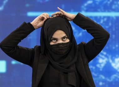 A female presenter for TOLOnews, Thamina Usmani, covers her face during a live broadcast at Tolo TV station in Kabul on May 22, 2022. (Wakil KOHSAR / AFP)