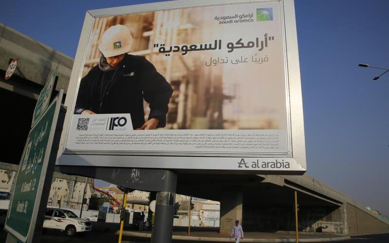 A man walks under a billboard displaying an advertisement for Saudi Arabia's state-owned oil giant Aramco with Arabic reading "Saudi Aramco, soon on stock exchange" in Jiddah, Saudi Arabia on Nov. 12, 2019. (AP Photo/Amr Nabil, File)