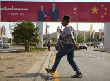 A woman crosses the street near a billboard commemorating the state visit of Chinese President Xi Jinping in Port Moresby, Papua New Guinea, Nov. 15, 2018. (AP Photo/Mark Schiefelbein, File)