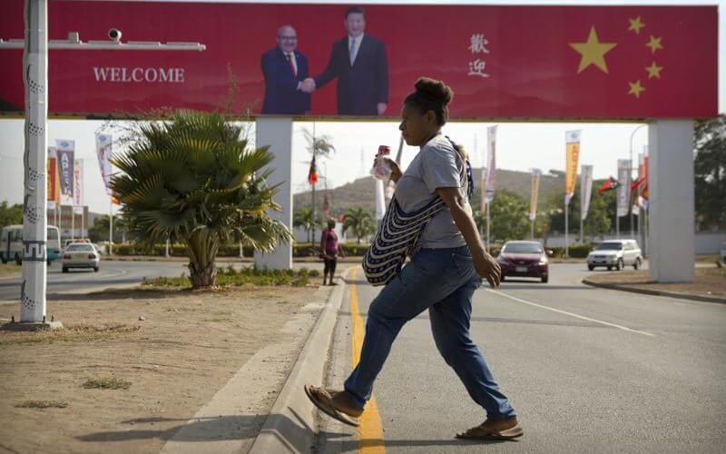 A woman crosses the street near a billboard commemorating the state visit of Chinese President Xi Jinping in Port Moresby, Papua New Guinea, Nov. 15, 2018. (AP Photo/Mark Schiefelbein, File)