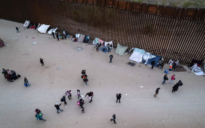 In an aerial view, migrants gather along the U.S. border wall from Mexico on Dec. 10, 2021 in Yuma, Ariz. | John Moore/Getty Images