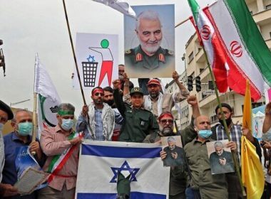 Iranians prepare to set an Israeli flag on fire next to a picture of late Iranian general Qasem Soleimnai during a rally marking al-Quds (Jerusalem) day in Tehran, on April 29, 2022. (AFP)