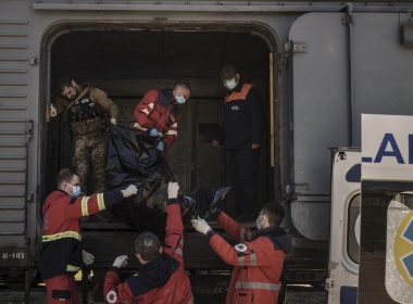 A Ukrainian serviceman and emergency workers carry the body of a Russian soldier into a refrigerated train in Kharkiv, Ukraine, Thursday, May 5, 2022. The bodies of more than 40 Russian soldiers who were found after battles around Kharkiv are being stored in the refrigerated car. (AP Photo/Felipe Dana)