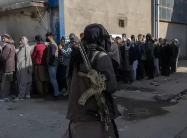 A Taliban fighter secures the area as people line up for a money distribution organized by the World Food Program in Kabul, Afghanistan, on Nov. 17, 2021. (AP Photo/ Petros Giannakouris)