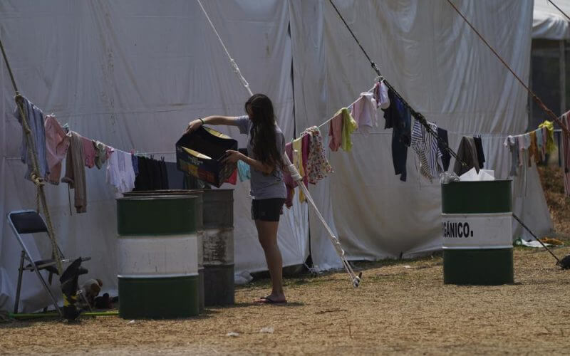 A young Ukrainian refugee woman disposes of the garbage at a camp in Utopia Park, Iztapalapa, Mexico City, Monday, May 2, 2022. (AP Photo/Marco Ugarte)