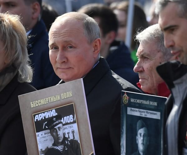 Russian President Vladimir Putin and other participants carry portraits of their relatives — World War II soldiers — as they take part in the Immortal Regiment march on May 9, 2022, in Red Square in central Moscow. Russia celebrates the 77th anniversary of the victory over Nazi Germany in World War II. (Natalia Kolesnikova/AFP via Getty Images)