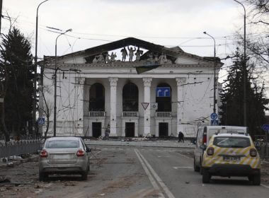 People walk past the Donetsk Academic Regional Drama Theatre in Mariupol, Ukraine, following a March 16, 2022, bombing of the theater, which was used as a shelter, in an area now controlled by Russian forces on Monday, April 4. The bombing stands out as the single deadliest known attack against civilians to date in the Ukraine war. (AP Photo/Alexei Alexandrov, File)