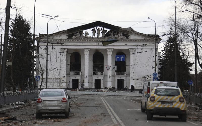 People walk past the Donetsk Academic Regional Drama Theatre in Mariupol, Ukraine, following a March 16, 2022, bombing of the theater, which was used as a shelter, in an area now controlled by Russian forces on Monday, April 4. The bombing stands out as the single deadliest known attack against civilians to date in the Ukraine war. (AP Photo/Alexei Alexandrov, File)