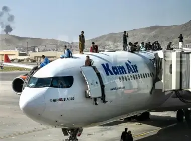 Afghan people climb atop a Kam Air plane as they wait at the airport in Kabul on August 16, 2021, after a stunningly swift end to Afghanistan's 20-year war.Wakil Kohsar / AFP via Getty Images