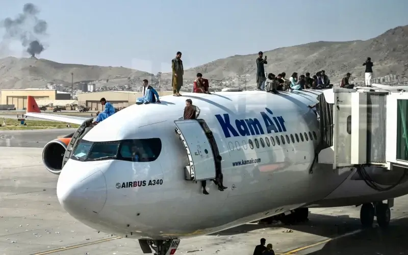 Afghan people climb atop a Kam Air plane as they wait at the airport in Kabul on August 16, 2021, after a stunningly swift end to Afghanistan's 20-year war.Wakil Kohsar / AFP via Getty Images