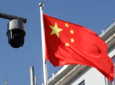 The Chinese flag flies behind a surveillance camera / Reuter