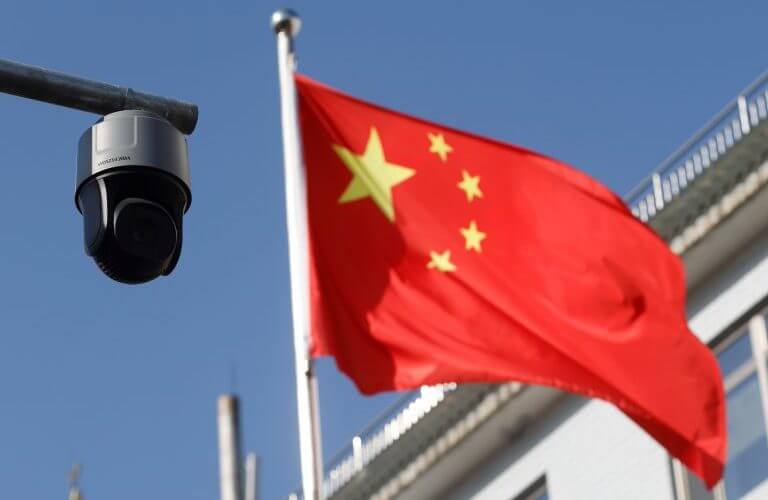 The Chinese flag flies behind a surveillance camera / Reuter