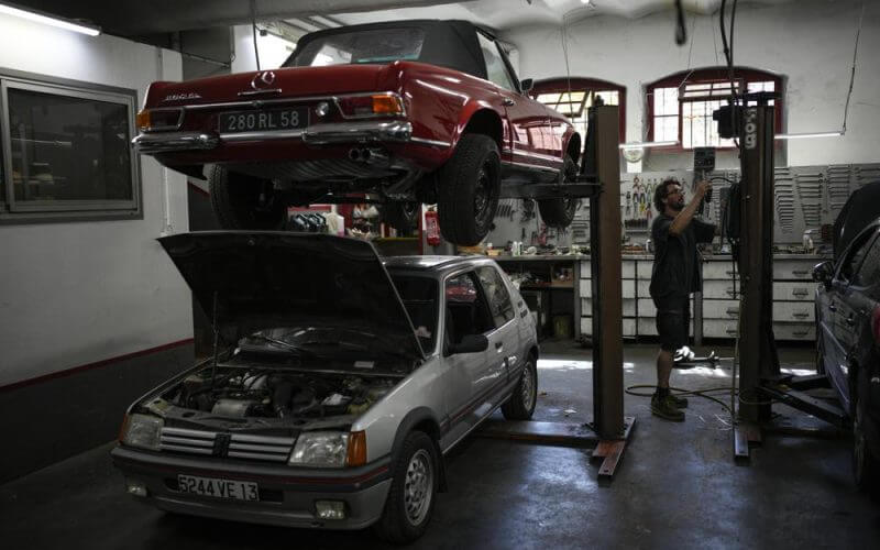 Mechanic Frederic Mistre works on a combustion engine car at a garage in Marseille, southern France, Wednesday, June 8, 2022. (AP Photo/Daniel Cole)